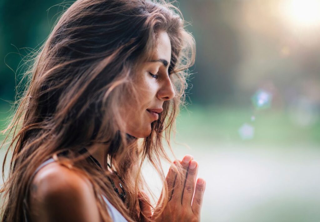 a woman with her hands together in prayer